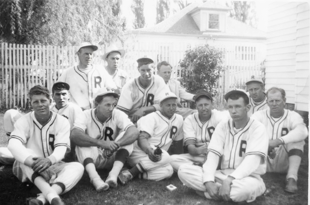 Leo Davis (back right), sports editor for the Spokesman, poses in this photograph with one of Redmond's community baseball teams sometime in the early 1950s. The team included, from left to right, (first row) Bud Van Matre, Harley Hart, Harold Povey, Jack Hassler, Marv Scott, Ray Douglas, Vern Hassler, and Hank Cooper; (second row) George Taylor, Riley Sanders, Jim Griffith, and Leo Davis.